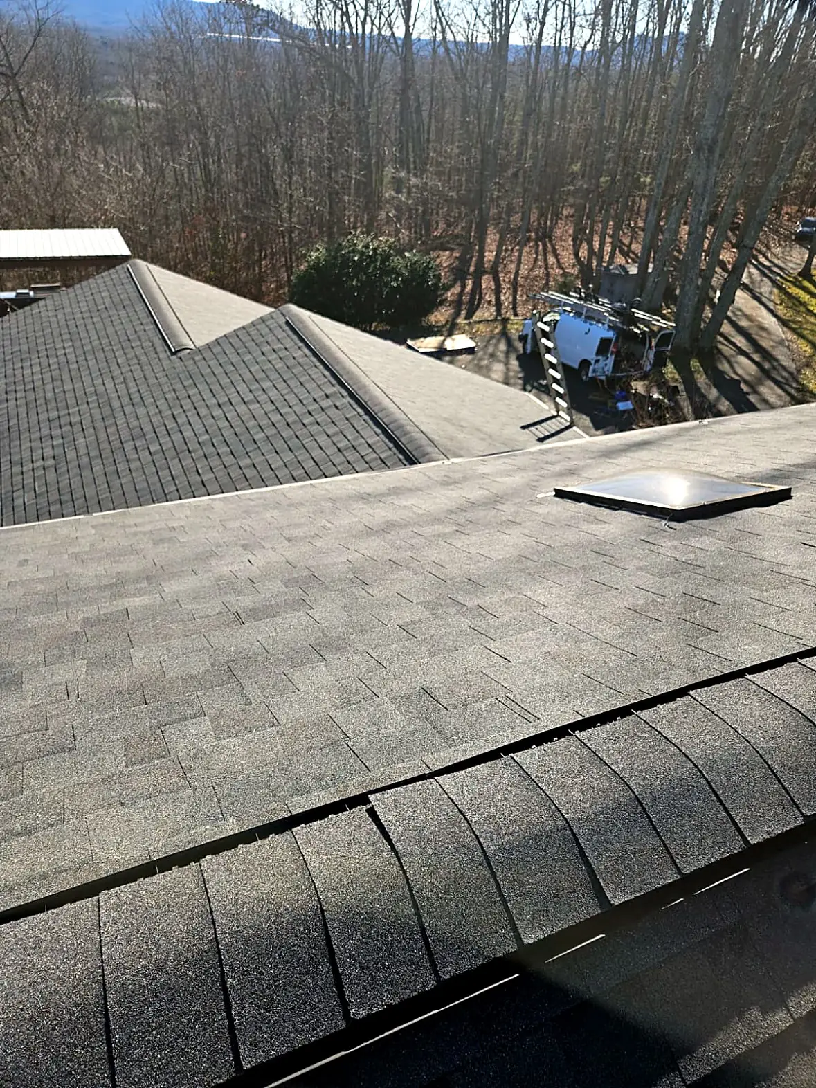 Finished architectural shingle roof with a skylight and new ridge cap, trees and hills behind, Kings Mountain NC